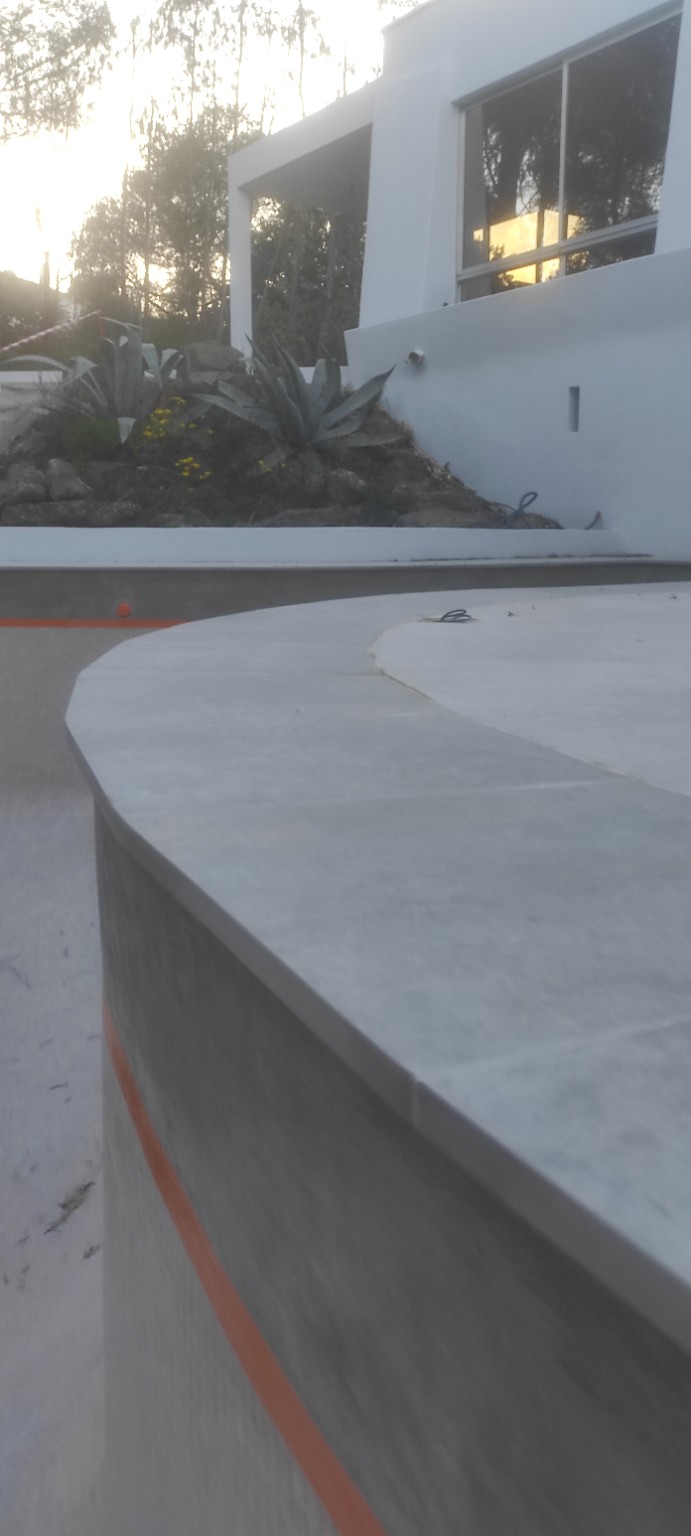Ouvrage extérieur en béton aux lignes courbes devant une façade de villa